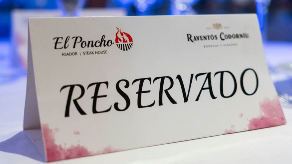 Cartel de mesa reservada con logotipo de El Poncho sobre mantel blanco.