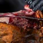 Corte de jamón ibérico a cuchillo realizado por profesional dentro del restaurante El Poncho