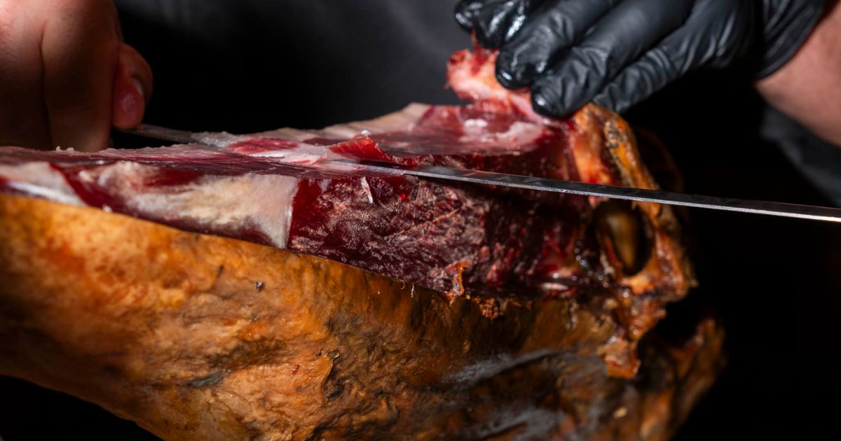 Corte de jamón ibérico a cuchillo realizado por profesional dentro del restaurante El Poncho