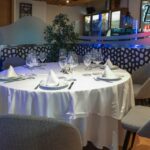 Sala interior del restaurante El Poncho con mesa redonda, vinoteca iluminada y zona de comensales.